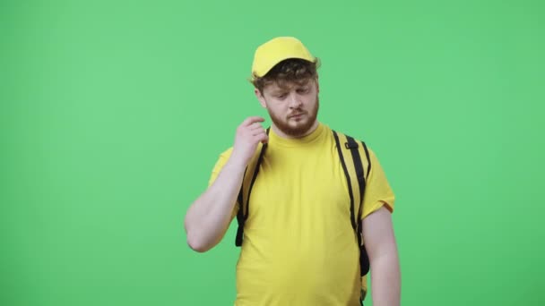 Portrét mladíků o něčem přemýšlí a pak ho něco napadne. Muž ve žluté doručovací uniformě s termosáčkem pózujícím na zelené obrazovce. Zavřít. Zpomalení připraveno 59.97fps. — Stock video