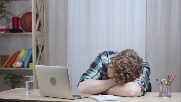 Jonge vermoeide man in geruite shirt slaapt aan tafel, wordt wakker en typt op laptop toetsenbord. Roodharige man met een baard op kantoor. Sluit maar af. Slow motion klaar 59,97 fps. — Stockvideo