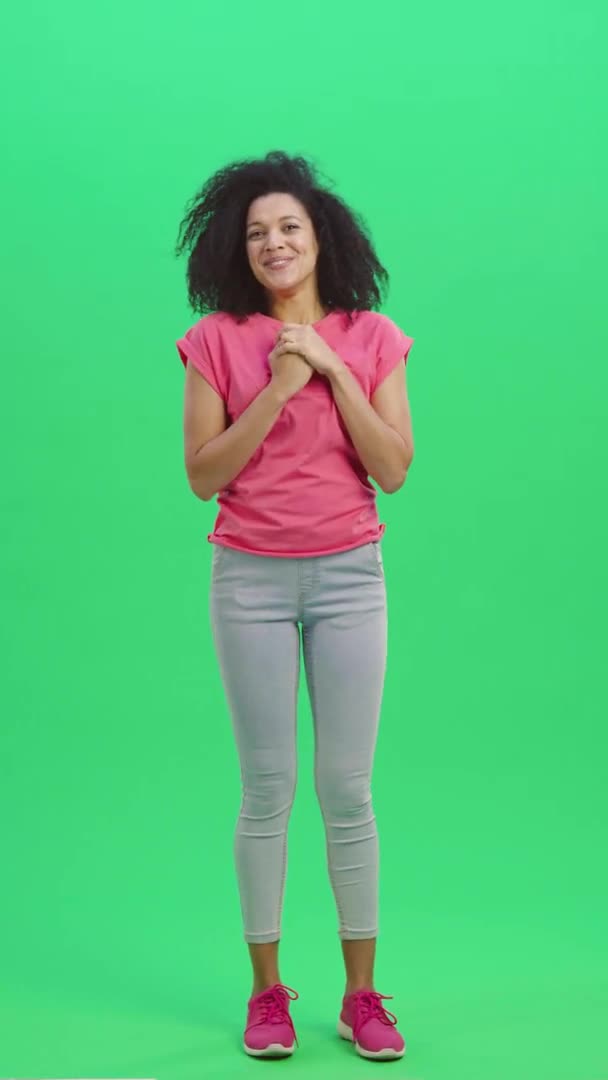 Porträtt av unga kvinnliga afroamerikanska leende söt och mycket glad. Svart kvinna med lockigt hår poserar på grön skärm i studion. Slow motion klar 59,97fps. fp. Vertikal video. Full längd. — Stockvideo