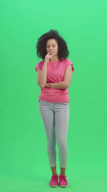 Genç Afrikalı Amerikalı kadın portresi düşünüyor ve sonra aklına bir fikir geliyor. Kıvırcık saçlı siyah kadın yeşil ekranda poz veriyor. Yavaş çekim hazır 59.97 fp. Dikey video. Tam uzunluk.