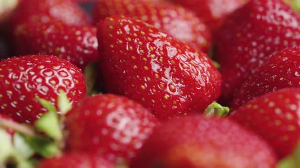 Fraises mûres juteuses recouvertes de gouttelettes d'eau tourner de près. Baies douces d'été avec queues vertes. Alimentation végétalienne biologique saine. Vitamine fruits sains. — Video