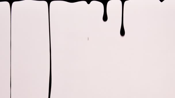 Black paint slowly drips down on white background. Dynamic animation of thick liquid dripping down. Drops ink. Spilling paint. Graphic wallpaper with spilled paint effect. — Stock Video