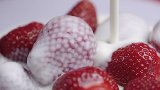 Häll grädde eller yoghurt över saftiga färska jordgubbar. Söta röda bär täckta med en vit mjölkaktig vätska. Vitamin hälsosam dessert, hälsosam mat. Närbild. Långsamma rörelser. — Stockvideo
