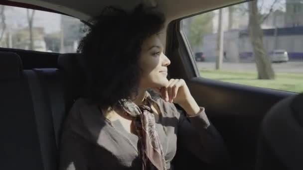 Portret van een stijlvolle jonge Afro-Amerikaanse vrouw die uit het raam kijkt en aan iets denkt. Een gemengd race vrouwtje rijdend in een auto op de achterbank. Sluit maar af. Slow motion klaar 59,97 fps. — Stockvideo