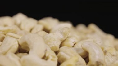 Bir avuç taze kaju siyah arka planda döner. Lezzetli, sağlıklı fındık çekirdekleri. Fındık arkaplan, sağlıklı yemek, diyet. Yavaş çekim hazır 59.94fps.