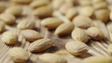 Ahşap bir masa yüzeyinde duran kurumuş badem kayması. Tüm kahverengi çekirdekler masaya saçılmış. Organik sağlıklı gıda geçmişi. Yavaş çekim hazır 59.94fps.