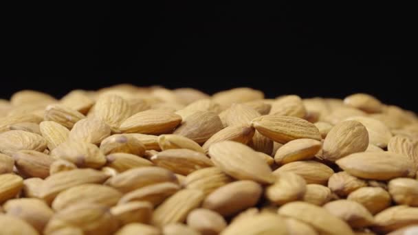 Un puñado de almendras secas rotan sobre un fondo negro. Núcleos de deliciosas nueces saludables de cerca. Nueces enteras. Antecedentes descabellados, comida sana, dieta. Cámara lenta lista 59.94fps. — Vídeo de stock