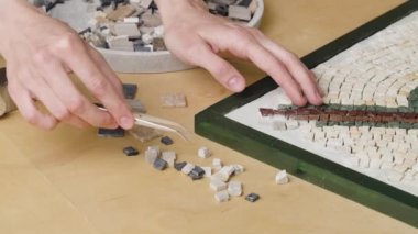 Erkek eller cımbız ve küçük granit taş parçaları kullanarak mozaik desenler oluştururlar. Usta yaratıcı atölyede el işi yapıyor. İlginç bir hobi, sanat, sanat. Kapatın. Yavaş çekim hazır 59.94fps