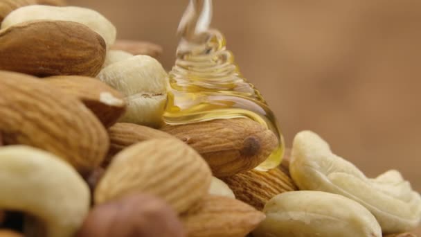 Ein Rinnsal goldenen Honigs fließt in Zeitlupe einen Haufen Nüsse hinunter. Honig tropft und umhüllt die Mischung aus Mandeln, Cashewnüssen und Haselnüssen. Detailaufnahme von Nüssen in süßem Sirup. — Stockvideo