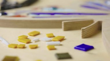 Erkek eller cımbızla, parlak cam ve seramiklerle mozaikler oluştururlar. Usta zanaatkar yaratıcı bir atölyede renkli kelebek desenleri yapıyor. Kapatın. Yavaş çekim hazır 59.94fps.