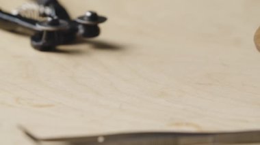 Meme ucu aletinin detaylı makro görüntüsü ve mozaik düzenlemek için cımbız. Mozaik desen oluşturmak için masaya renkli taşlar dökülüyor. Kapatın. Yavaş çekim.