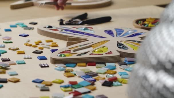 Male hands create mosaics with tweezers and bright little pieces of glass and ceramics. Master craftsman making colorful butterfly pattern in a creative workshop. Close up. Slow motion. — Stock Video