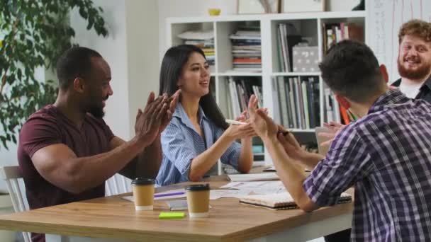 Boas startups criativas batem palmas durante a sessão de brainstorming corporativa no escritório moderno. Os colegas da equipe multinacional celebram o bom resultado bem sucedido do trabalho conjunto no briefing de companhia. Movimento lento. — Vídeo de Stock