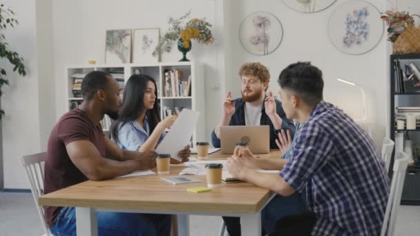 Friendly team di colleghi creativi diversi discutere progetto di avvio. Gruppo di colleghi multietnici seduti a tavola in un ufficio moderno e che discutono di questioni commerciali nella riunione di negoziazione. Rallentatore. — Video Stock