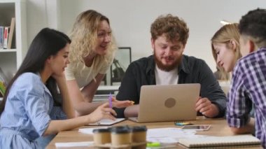 Modern ofiste masada oturan ve müzakere toplantısında iş konularını tartışan bir grup genç erkek ve kadın. Nitelikli çalışanlar başlangıç pazarlama stratejisi geliştiriyor. Ağır çekim. Kapat..