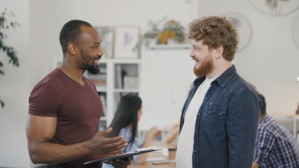 Dois colegas trabalhando juntos discutindo o trabalho em equipe e lançando um novo projeto de negócio de startup. Homens conversando, rindo trabalhando juntos na reunião de negócios do grupo corporativo. Movimento lento. — Vídeo de Stock