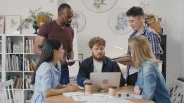 Meslektaşlar yeni bir strateji hakkında konuşuyor. Çok ırklı bir grup insan evrak işlerini analiz eder brifing masasında toplanır, modern ofiste başlangıç projesi planını tartışırlar. Yavaş çekim.