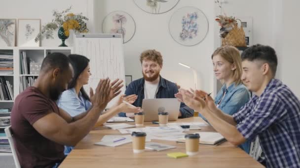 Le startup creative felici applaudono durante la sessione di brainstorming aziendale in ufficio moderno. I colleghi di team multinazionale festeggiano il buon risultato di successo di lavoro comune a briefing d'azienda. Rallentatore. — Video Stock