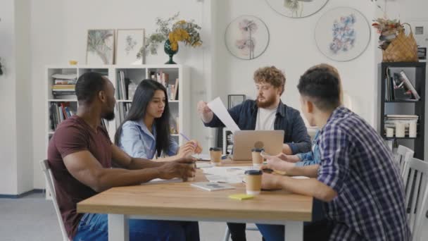 Friendly team di colleghi creativi diversi discutere progetto di avvio. Gruppo di colleghi multietnici seduti a tavola in un ufficio moderno e che discutono di questioni commerciali nella riunione di negoziazione. Rallentatore. — Video Stock