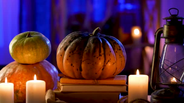 Há uma lâmpada de óleo, velas em chamas e abóboras na mesa no quarto decorado para o Halloween. O fundo está desfocado. Decoração para a celebração do Halloween. Aproxima em câmara lenta. Fechar. — Vídeo de Stock