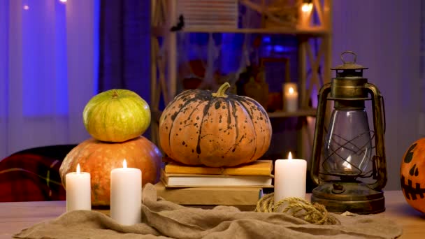 Hay una lámpara de aceite, velas encendidas y calabazas en la mesa en la habitación decorada para Halloween. El fondo está borroso. Decoración de Halloween. Zoom en cámara lenta. — Vídeos de Stock