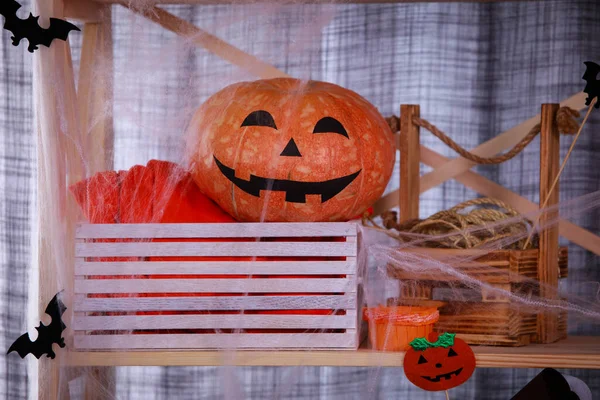 Festive mystique intérieur d'Halloween. Sur l'étagère de la pièce, il y a des symboles traditionnels d'Halloween, une citrouille effrayante, des toiles d'araignée, des chauves-souris en papier. Gros plan. — Photo