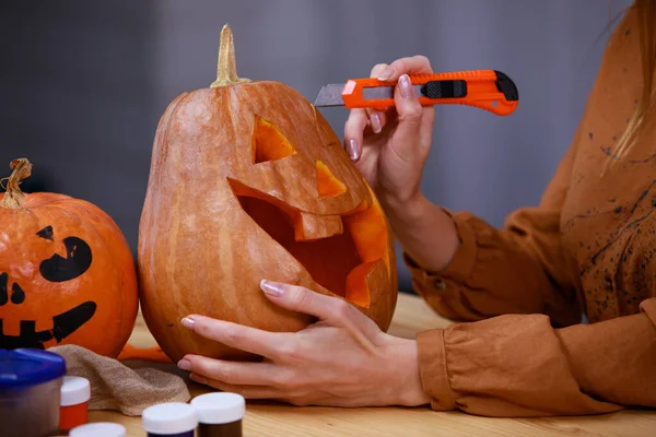 Je me prépare pour Halloween. Gros plan d'une main de femme sculptant une lanterne Jack o d'une citrouille. Vacances et Halloween concept de décoration. — Photo