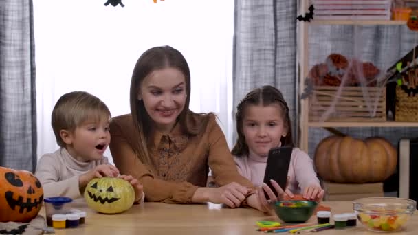 Rodina dělá videohovor na telefonu na otce nebo příbuzné, vlny a demonstruje halloweenské dekorace, které provedli na partnera, členové posílají polibky. Zpomal. Zavřít. — Stock video