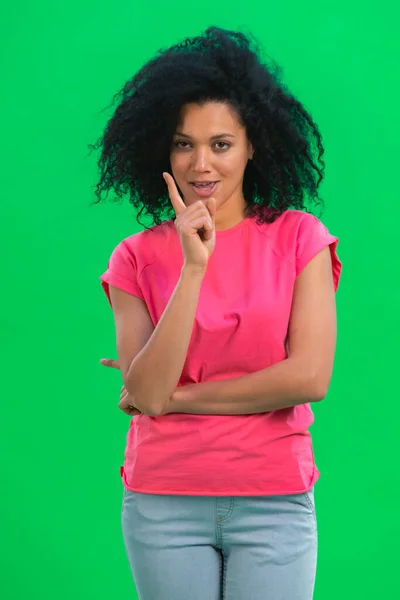 Portrett av unge kvinnelige afroamerikanere skjelver kraftig med pekefingeren. En svart kvinne med krøllete hår poserer på en grønn skjerm i studioet. Lukk. – stockfoto