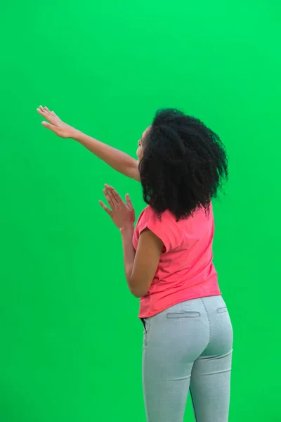 Genç Afrika kökenli Amerikalı bir kadının bir şey düşünüp seçmesi. Pembe tişörtlü kıvırcık saçlı siyah kadın stüdyoda yeşil ekranda poz veriyor. Kapat.. — Stok fotoğraf