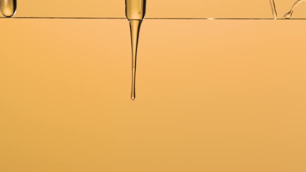 Makro lövés sűrű folyékony cseppek méz folyik le az üvegen, és esik le a barna stúdió háttér lágy fény. Arany édes méz csöpögő vonalak édes folyadék. Közelről. Lassú mozgás.. — Stock videók