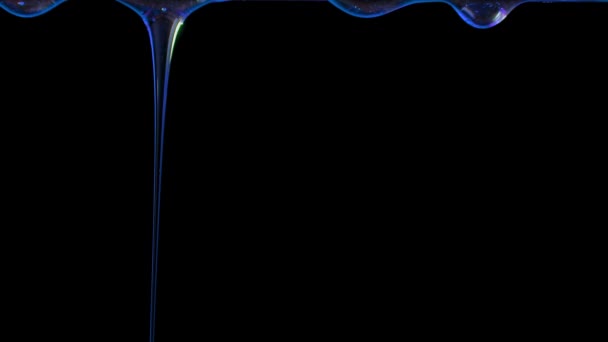 Gotas de miel iluminadas con luz azul gotean sobre un fondo de estudio negro. El líquido espeso dulce gotea hacia abajo. Jarabe de colores transparentes o gotas de aceite que fluyen hacia abajo. De cerca. Movimiento lento. — Vídeos de Stock