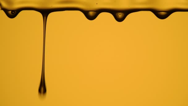 Темні краплі органічного натурального меду на жовтому фоні студії. Наливаємо мед, тече рідкий цукровий сироп, квітковий нектар. Повільний рух меду. Лікувальна складова. Близько. Повільний рух . — стокове відео