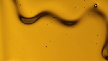 Makro, kahverengi arka planda yavaş bir bal akışını kapat. Bal ya da tatlı şurup dokusu derelerden aşağı akıyor, pekmez ya da çiçek nektarı dökülüyor. Tatlı doğal gıdaların güzel arka planı.