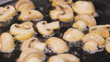 Şampiyonların altın dilimleri sıcak bir tavada kızartılır. Yakından yağla kaplanır. Pişmiş mantarlara baharat serpin. Akşam yemeği için sebze hazırlıyorum. Yavaş çekim.