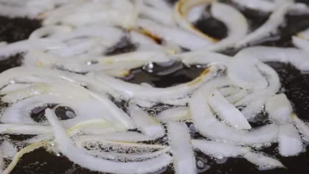 Cipolle bianche affettate che friggono in padella calda con olio. Macro shot di cottura cipolle fritte in padella. Mescolare la cipolla fritta con spatola rossa. Preparare le verdure per cucinare la cena. Chiudete. Rallentatore — Video Stock