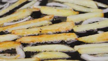 Altın çıtır patates ve soğan parçaları mutfakta sıcak bir tavada yağda kızartılır. Patates yemeği pişirme süreci. Restoran için güzel bir duvar kâğıdı. Yavaş çekim.