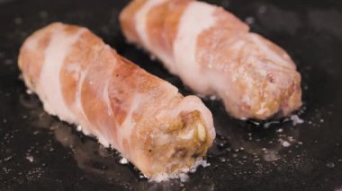 Beyaz damarlı pastırmaya sarılmış kıymalı etten yapılmış et yemeği. Chevapchichi 'ler kızgın tavada kızartılıyor. Restoran için güzel bir duvar kâğıdı. Ağır çekim. Kapat..