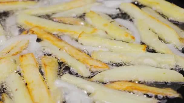 Zeppe dorate croccanti di patate e cipolle vengono fritte sott'olio in una padella calda in cucina. Il processo di cottura di un piatto di patate da vicino. Bella carta da parati di cottura per il ristorante. Rallentatore. — Video Stock