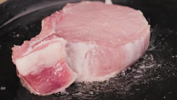 Le steak de porc cru est frit dans de l'huile bouillante dans une poêle chaude. Gros plan sur le processus de grillage d'un plat de viande. Je prépare le dîner. Beau fond d'écran de cuisine pour restaurant. Mouvement lent. — Video