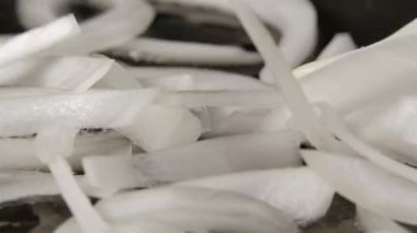 Dilimlenmiş beyaz soğanlar yağlı sıcak bir tavaya dökülür. Kızartma tavasında kızarmış soğan pişirme makrosu. Akşam yemeği için sebze hazırlıyorum. Kapatın. Yavaş çekim.