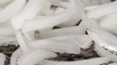 Dilimlenmiş beyaz soğanlar yağlı sıcak bir tavada kızartılıyor. Kızartma tavasında kızarmış soğan pişirme makrosu. Akşam yemeği için sebze hazırlıyorum. Kapatın. Yavaş çekim.