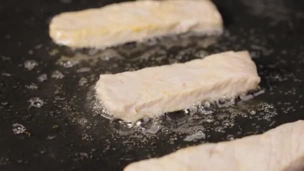 As tiras do filete de frango fritam-se no óleo em uma panela quente. Pedaços de peru suculentos são fritos. Close up tiro de cozinhar prato de carne saudável suculento. Papel de parede bonito de cozinhar para restaurante. Movimento lento. — Vídeo de Stock