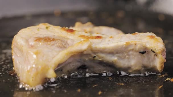 Un morceau appétissant de steak de porc est frit dans de l'huile bouillante dans une poêle chaude. L'huile de tournesol bulle et enveloppe la viande. Macro shot du processus de grillage d'un plat de viande. Je prépare le dîner. Mouvement lent. — Video