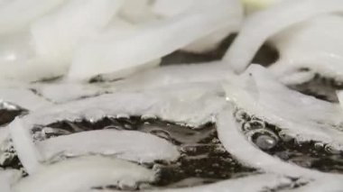 Dilimlenmiş beyaz soğan, yağlı sıcak tavada kızartılıyor. Kızartma tavasında kızarmış soğan pişirme makrosu. Kırmızı spatula ile kızartılmış soğan. Akşam yemeği için sebze hazırlıyorum. Kapatın. Yavaş çekim