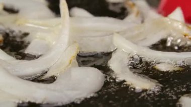 Dilimlenmiş beyaz soğan, yağlı sıcak tavada kızartılıyor. Kızartma tavasında kızarmış soğan pişirme makrosu. Kırmızı spatula ile kızartılmış soğan. Akşam yemeği için sebze hazırlıyorum. Kapatın. Yavaş çekim