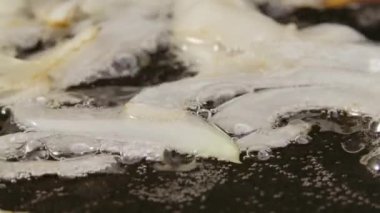 Dilimlenmiş beyaz soğan, yağlı sıcak tavada kızartılıyor. Kızartma tavasında kızarmış soğan pişirme makrosu. Kırmızı spatula ile kızartılmış soğan. Akşam yemeği için sebze hazırlıyorum. Kapatın. Yavaş çekim