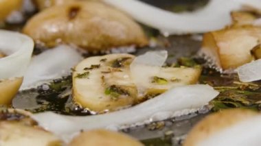 Kızarmış şampiyon mantarlarını kızartma tavasında zeytinyağlı soğanla pişirme işlemi. Kırmızı spatuladan kızarmış soğan ve şampiyonlar. Makro atış. Yavaş çekim.