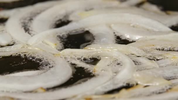 Les oignons blancs tranchés sont frits dans une poêle chaude avec de l'huile. Macro shot de cuisson des oignons frits dans une poêle. Préparation des légumes pour le dîner. Ferme là. Mouvement lent. — Video