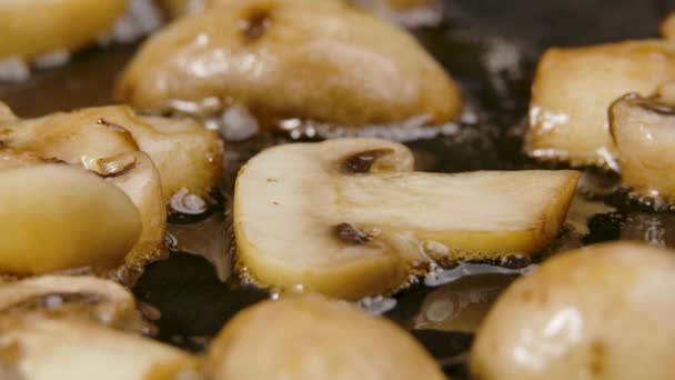 Les champignons champignon tranchés sont frits dans une poêle chaude en gros plan. Des tranches dorées de champignons sont frites à l'huile d'olive. Beau fond d'écran de cuisine pour restaurant. Mouvement lent. — Video